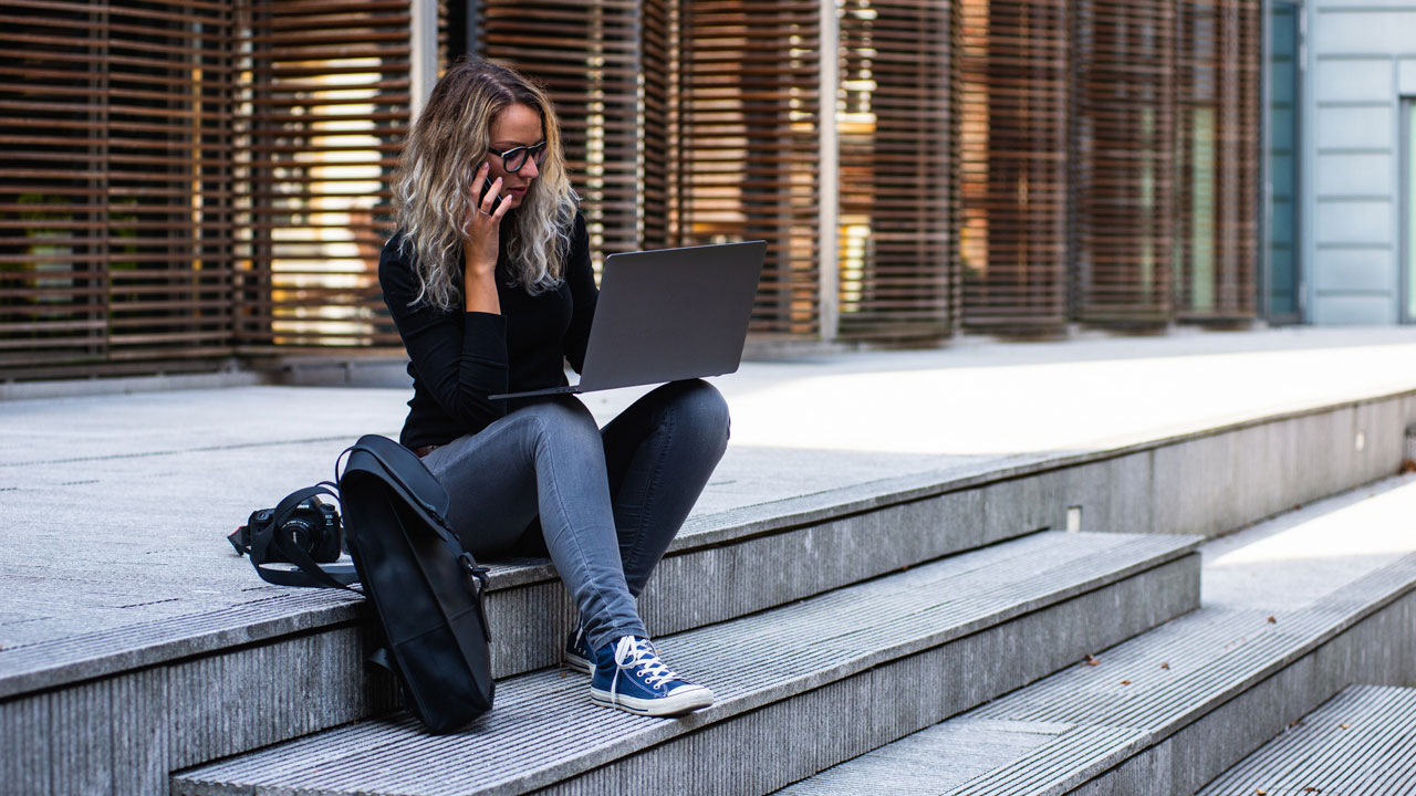 kvinna sitter i en trappa utomhus med sin laptop i knät