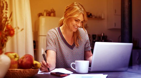 kvinna framför sin laptop som jobbar hemifrån